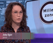 Afbeelding uit de uitzending van Max Meldpunt. Ik zit in de studio, over mijn borst een balkje met mijn naam en "jurist", op de achtergrond een bord van een milieuzone. Ik ben een indo vrouw met golvend donker haar, ik draag een blousejurk met patroon en een dun bruin montuur bril, ik praat naar rechts buiten beeld.